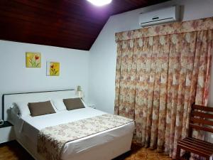 ein Schlafzimmer mit einem weißen Bett und einem Vorhang in der Unterkunft Hotel Akropolis in Serra Negra