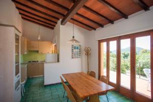 a kitchen with a wooden dining table and a balcony at Residence le Mimose in Lacona