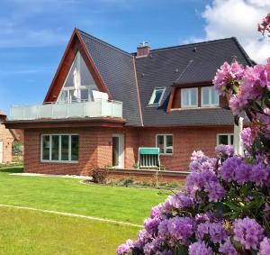 a red brick house with a cross on the roof at Lerchenhof in Wenningstedt