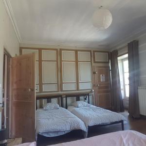 a bedroom with two beds and a wall with windows at Relais des castors in Murat