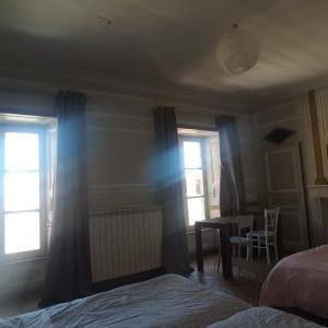 a bedroom with two windows and a table and a bed at Relais des castors in Murat