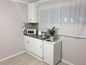 Una cocina con gabinetes blancos y un microondas en una encimera. en Ocean Breeze, en Mossel Bay