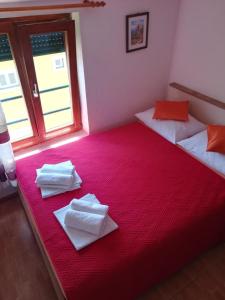 a bedroom with two beds with towels on a red blanket at Apartments Knežić in Igrane