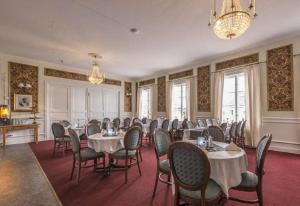 une salle à manger avec des tables et des chaises ainsi qu'un lustre dans l'établissement Hedemora Stadshotell, à Hedemora