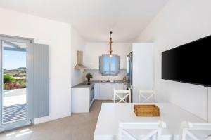 a white kitchen with a dining table and a tv at Agkairia´s House in Angairiá