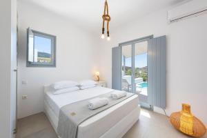 Un dormitorio blanco con una cama y un balcón. en Agkairia´s House, en Angairiá 21 fotos más
