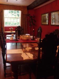 a dining room with a wooden table and red walls at Braithwaite Hall Bed & Breakfast in Middleham