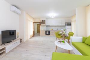 a living room with a green couch and a kitchen at Domus Apartments Grand in Plovdiv