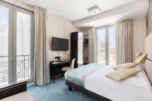 a hotel room with a bed and a desk and window at Best Western Hôtel Journel Antibes Juan-les-Pins in Antibes