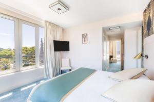 a white bedroom with a large bed and windows at Best Western Hôtel Journel Antibes Juan-les-Pins in Antibes