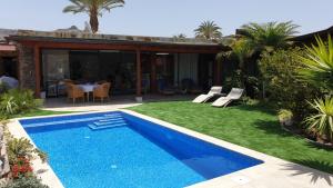 a yard with a blue swimming pool and a house at Villa Luxe Tauro Mogan in Puerto Rico de Gran Canaria