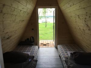 two beds in a room with a door and a window at Vigio Brasta camping in Elektrėnai