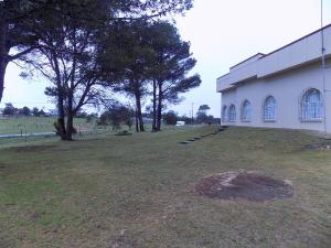 un bâtiment blanc avec un champ et des arbres en arrière-plan dans l'établissement Haka Hana B&B The Farm House, à Port Elizabeth