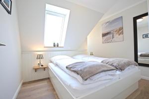 a white bedroom with white walls and a window at Villa Petersen "Himmel & Meer" in Wangerooge