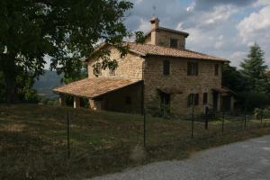 una vieja casa de piedra en una colina con una valla en Agriturismo Colle del Sole, en San Martino in Colle