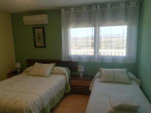 2 camas en una habitación verde con ventana en Aranaz Bardenas, en Cadreita