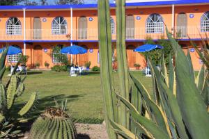 an orange building with blue umbrellas in the yard at Hotel SPA Villa San Agustin in Tecozautla