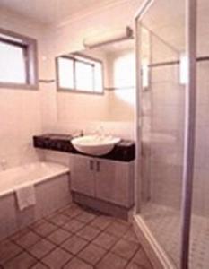 y baño con lavamanos, bañera y lavamanos. en Clayton Monash Motor Inn & Serviced Apartments, en Clayton North