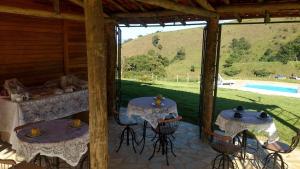 two tables in a pavilion with a view of a pool at Quinta do Papagaio in Pouso Alto