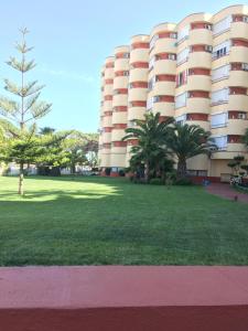 a large apartment building with palm trees in front of it at Estudio Loft in La Pineda