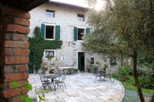 un patio avec des tables et des chaises en face d'un bâtiment dans l'établissement Casa Barnaba-Manin, à Trivignano Udinese