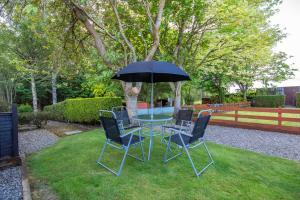 a table with chairs and an umbrella in a yard at Black Rock Cottage in Culbokie