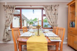 a dining room with a yellow table and chairs at Black Rock Cottage in Culbokie