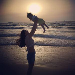 een vrouw die een kind vasthoudt op het strand bij studio by the sea in Ashdod