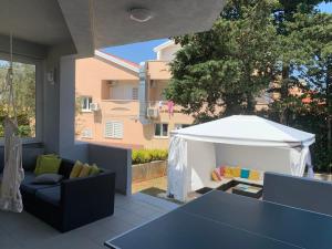patio z białym namiotem, kanapą i stołem w obiekcie Apartments Ana & Ita w Novalji