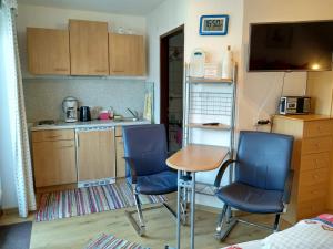 eine kleine Küche mit zwei Stühlen, einem Tisch und einer Theke in der Unterkunft Haus am Wiesenrain in Leutasch