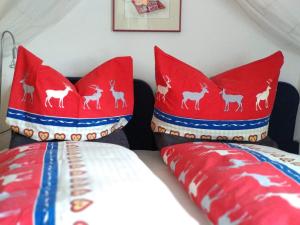 a bedroom with red pillows with deer on them at Haus am Wiesenrain in Leutasch
