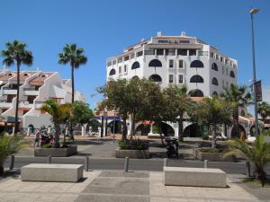 un grande edificio bianco con palme di fronte di Duplex Parque Santiago 2 close to pool, sea + beach, central, Wifi, heated pool a Playa de las Americas