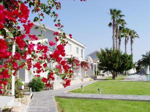 a white house with red flowers and palm trees at Mon Repos Hotel in Ayia Napa