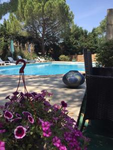 een zwembad met een bos bloemen en een vogelbeeld bij Hostellerie De La Source in Arles