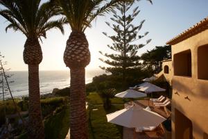 twee palmbomen met parasols en de oceaan bij Vila Joya in Albufeira