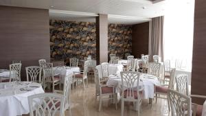 a dining room with white tables and white chairs at Hipotels Barrosa Park in Chiclana de la Frontera