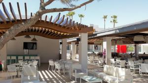 a restaurant with white chairs and tables and a tree at Hipotels Barrosa Park in Chiclana de la Frontera