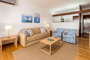 a living room with a couch and a chair at Apartamentos Turisticos Pinhal Da Marina in Vilamoura