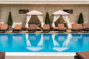 a large swimming pool with chairs and umbrellas at Hayat Spa Hotel in Pyatigorsk