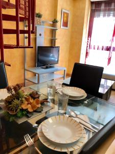 una sala da pranzo con tavolo in vetro e piatti di El Rincón de las Armas a Saragozza