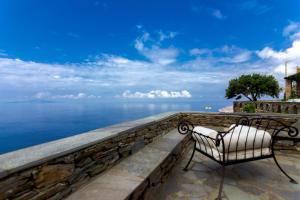 una panchina seduta su un muro che si affaccia sull'oceano di Andros Serenity Adults Only Residences a Episkopión