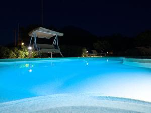 uma grande piscina azul à noite com um guarda-chuva em Naxos Cottage em Káto Sangríon