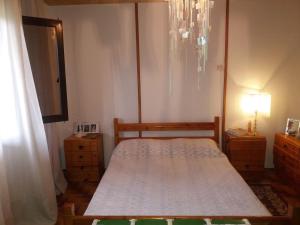 a small bedroom with a bed and a chandelier at Casa di Diamanto in Porto Rafti