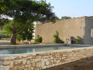 a swimming pool with a stone wall and a tree at A Loghja Di Cavallo Morto in Bonifacio