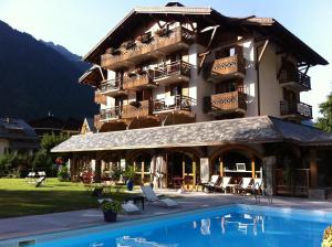 un hotel con piscina di fronte a un edificio di Oustalet a Chamonix-Mont-Blanc