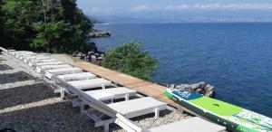 a row of lounge chairs and a surfboard on a beach at Boutique Hotel Acacia in Lovran