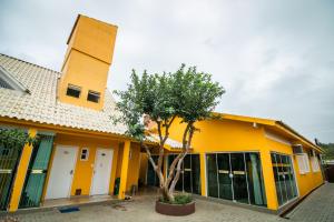 un edificio amarillo con un árbol delante de él en Pousada Nona Amabile, en São Lourenço do Sul