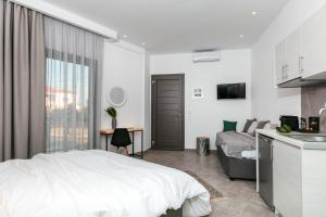 ein weißes Schlafzimmer mit Bett und Küche in der Unterkunft Delight Suites in Limenaria