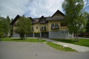 ein großes gelbes Haus mit einer Einfahrt davor in der Unterkunft Apartmán Lomnica in Tatranská Lomnica