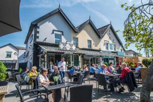 a group of people sitting at tables in front of a building at N'ista Boutique Rooms Birkdale, Southport in Southport